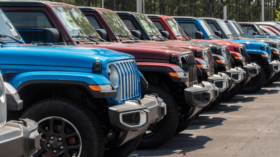 Row of colorful Jeep Wranglers parked at a dealership lot