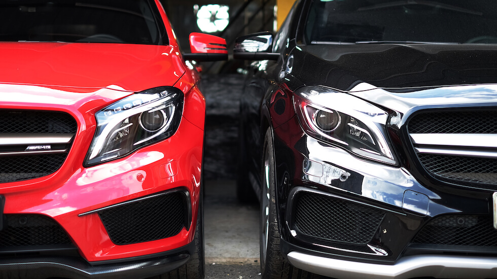 Two Mercedes-AMG cars, red and black, parked side by side