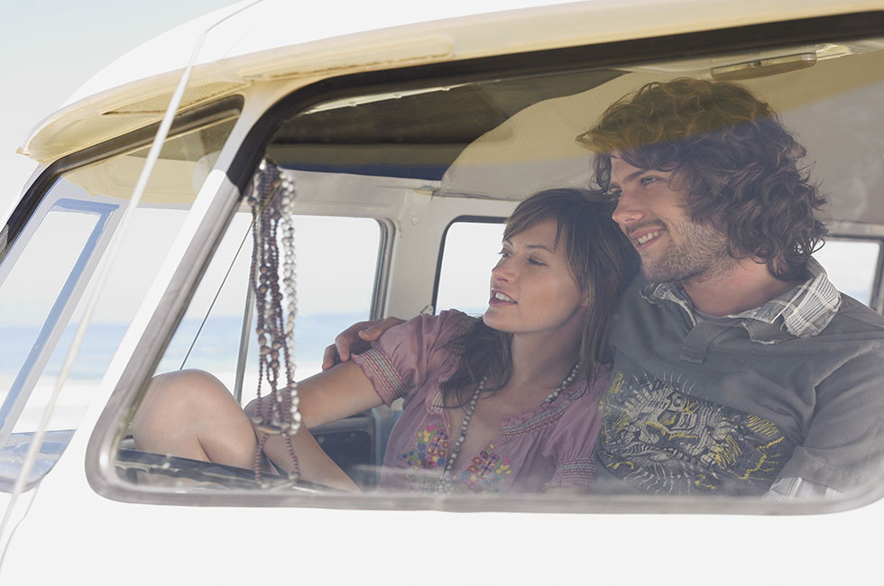 Smiling couple in vintage van, enjoying a road trip together