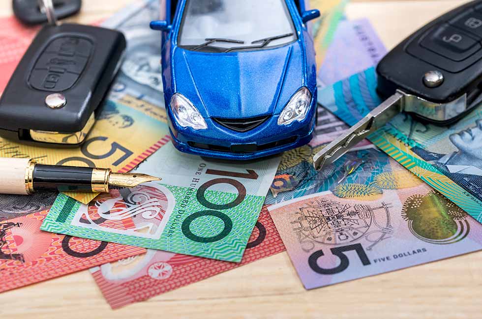 Blue toy car on Australian money with car keys and fountain pen