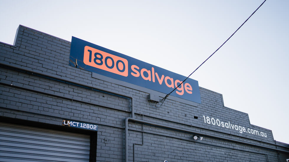 1800 Salvage sign on grey brick building with website and power line
