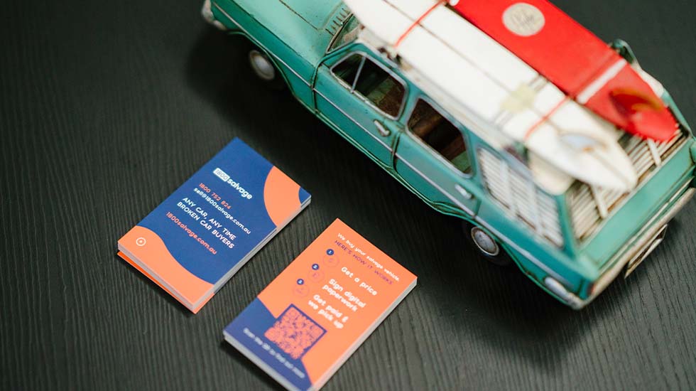 Vintage teal and red car with business cards on dark background