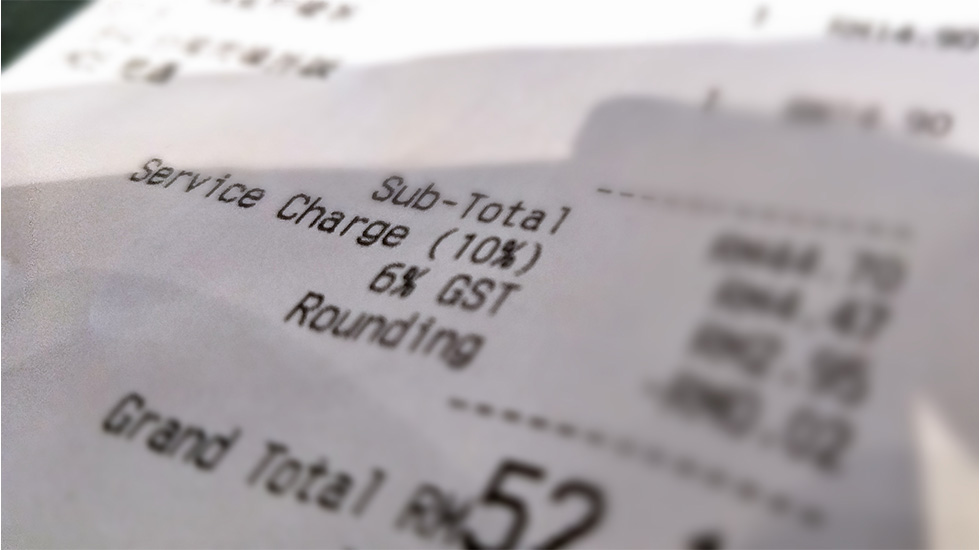 Close-up of restaurant receipt showing subtotal, service charge, and grand total