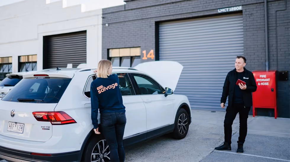 Two people talking beside a white Volkswagen car