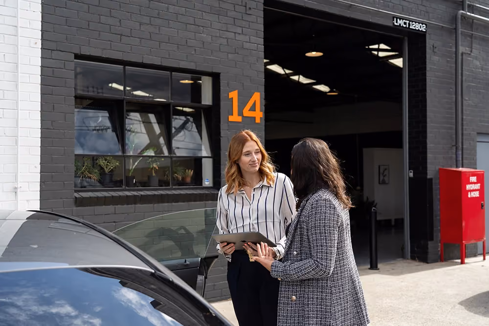 Two woman talking beside a car 