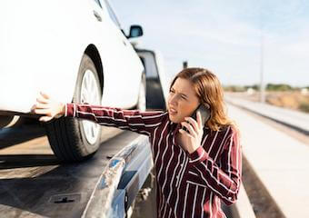 Woman on the phone as her broken down car gets towed