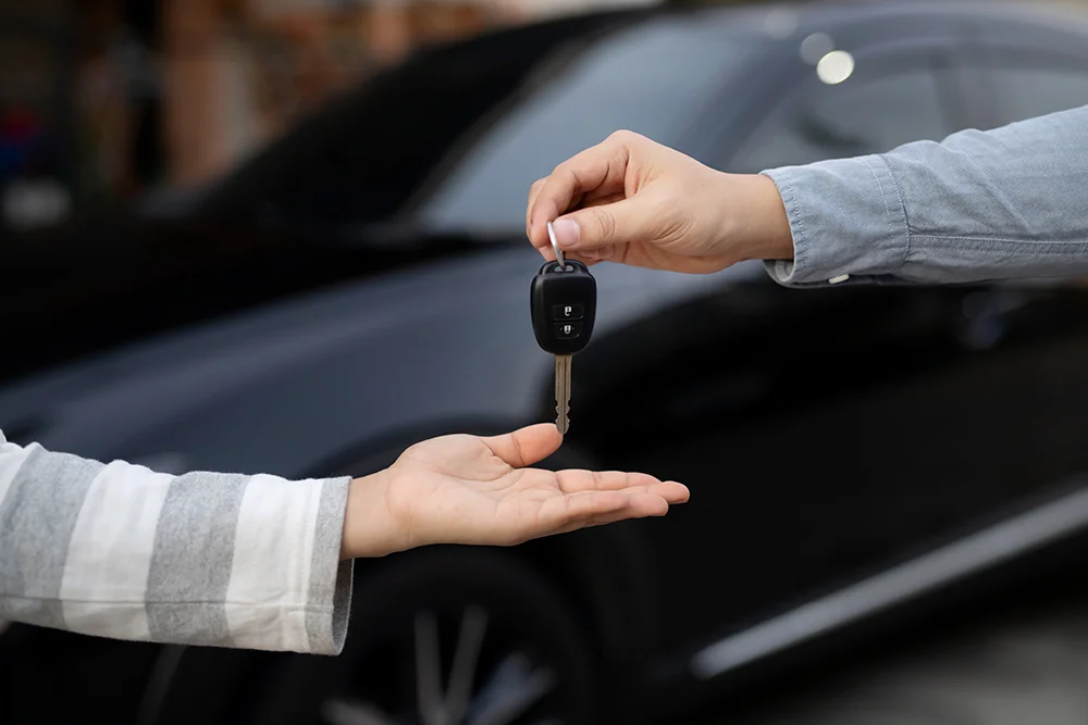 Close-up of one person handing over car keys to another