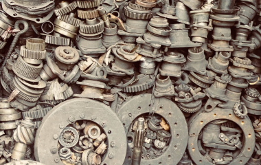 Metal scrap car parts piled up against a wall.