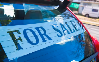 A ‘for sale’ sign stuck to the rear window of a red hatchback car in Sydney.