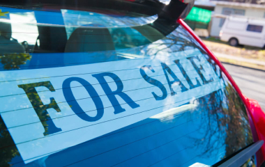 A ‘for sale’ sign stuck to the rear window of a red hatchback car in Sydney.