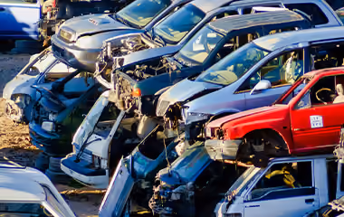 Piles of old cars in a scrap yard, waiting to be recycled.