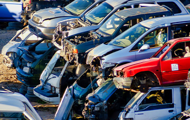 Piles of old cars in a scrap yard, waiting to be recycled.