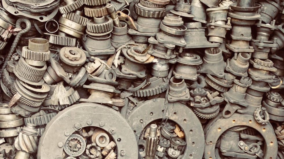 Metal scrap car parts piled up against a wall.