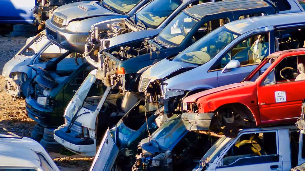 Piles of old cars in a scrap yard, waiting to be recycled.