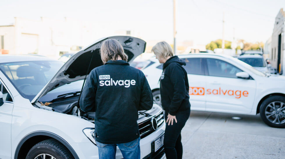 Salvage experts looking under a bonnet to see if the car engine is seized 