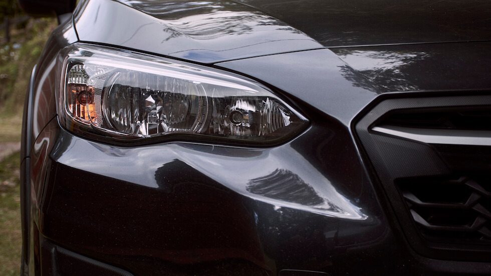 Front lights of a dark grey Subaru