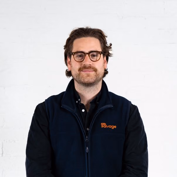 Man with glasses and beard wearing navy Salvage vest against white background