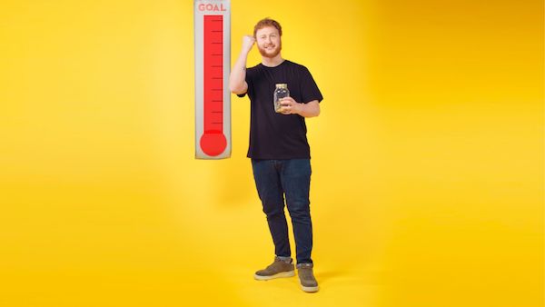 A man holding a money pot achieving his fundraising target.