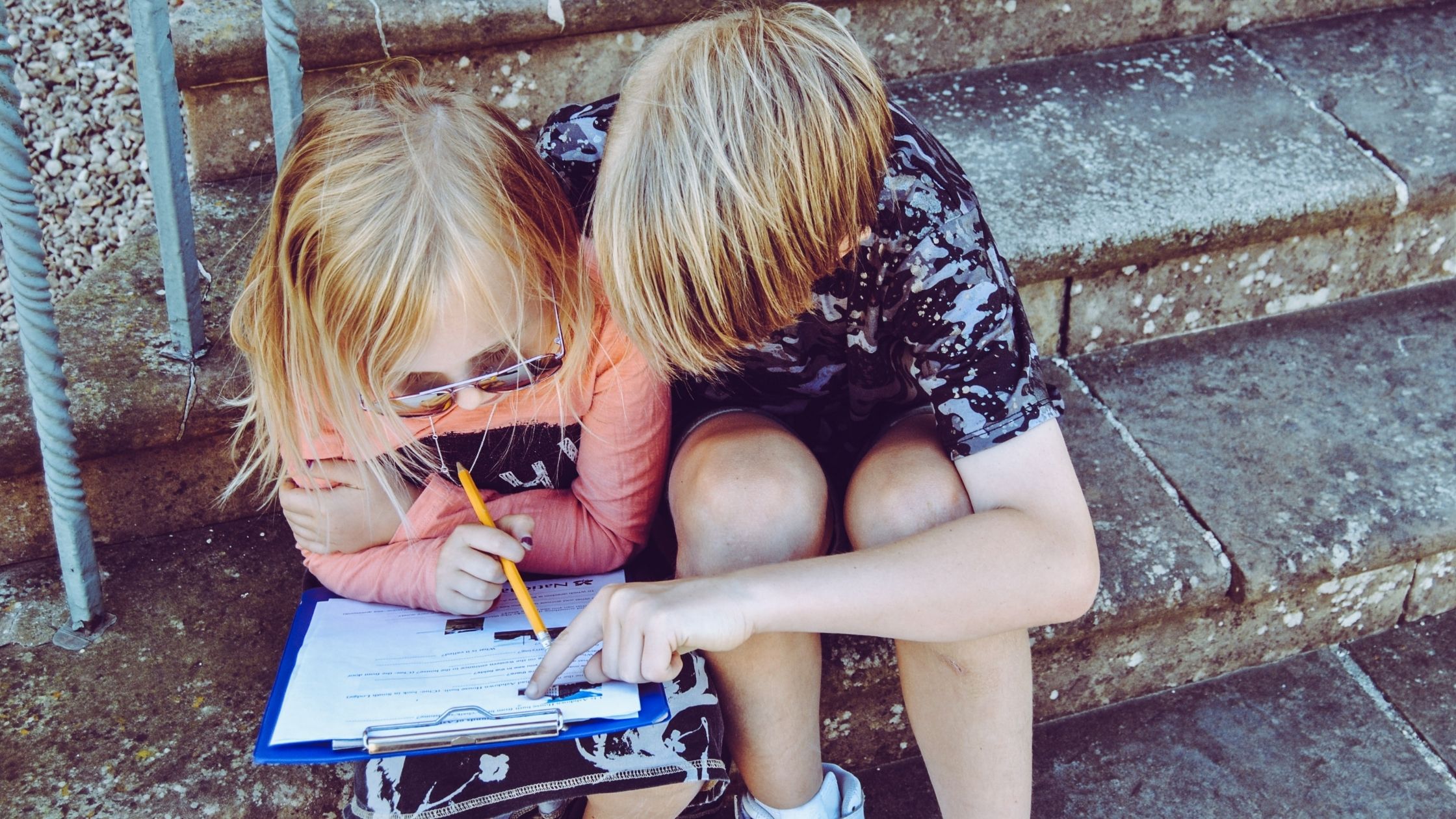 Two children huddled over a form