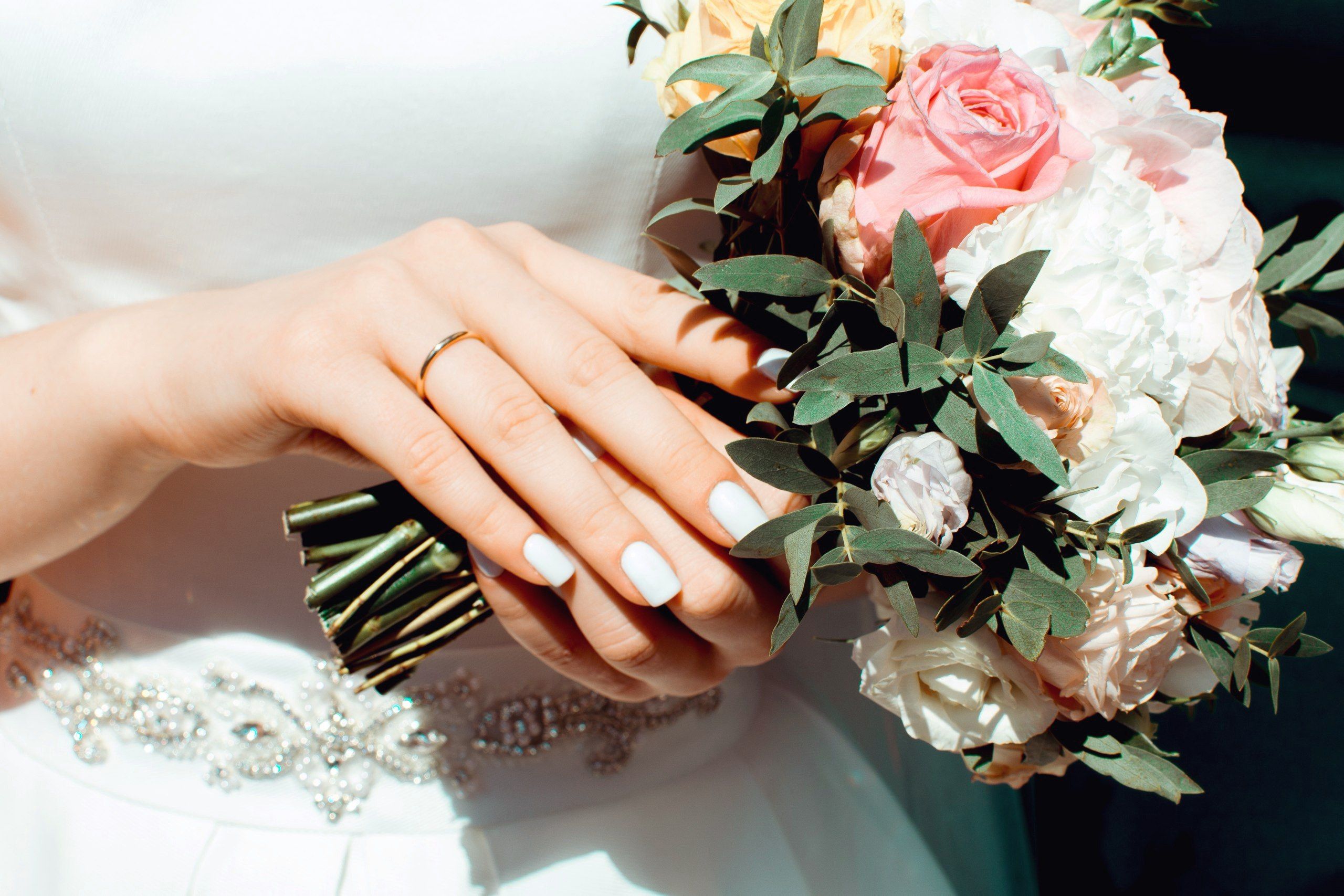 Close-up of a bride holding a beautiful wedding bouquet with an elegant ring on her hand