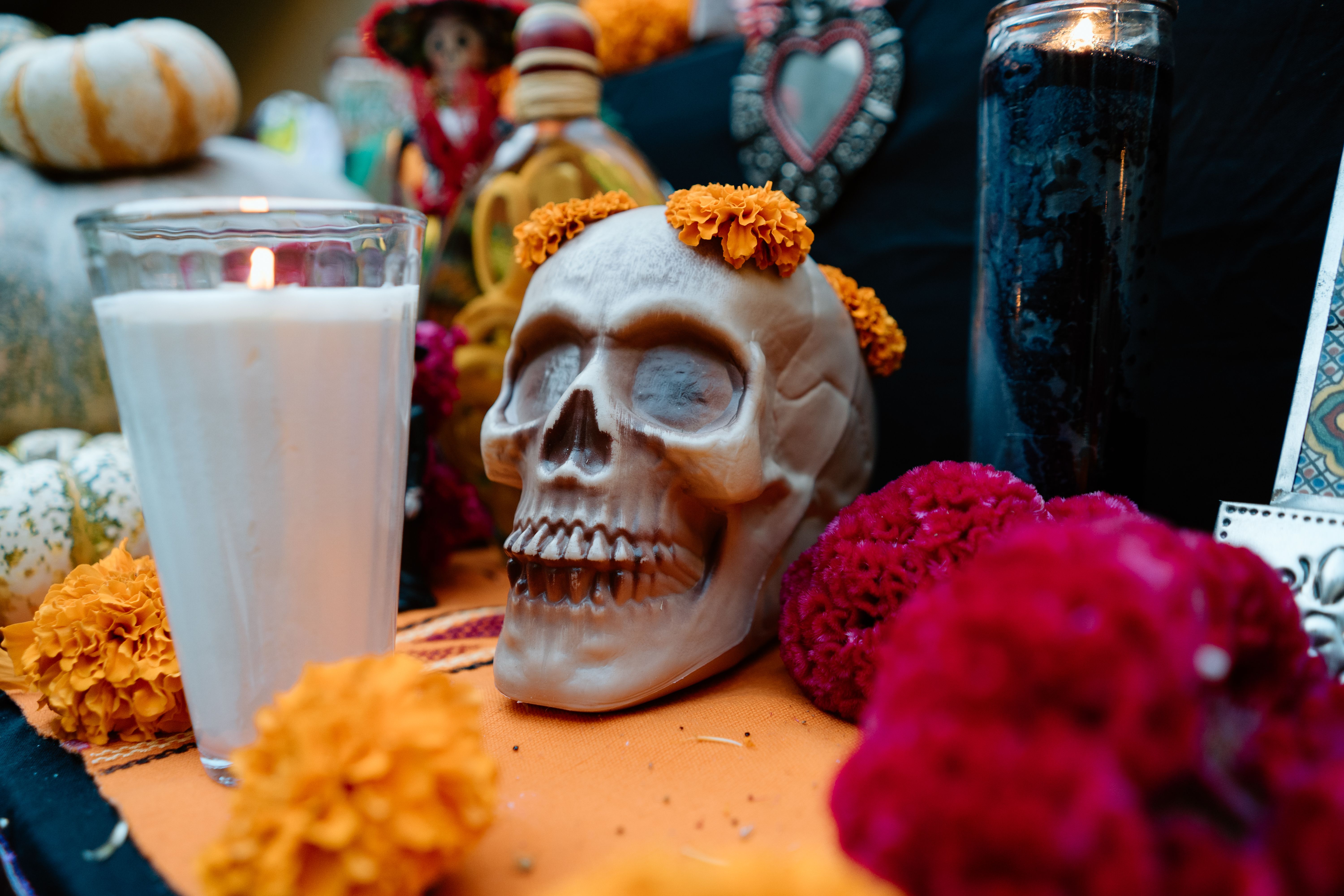 A colorful Día de Muertos altar featuring a skull with marigolds and lit candles, celebrating Mexican tradition.