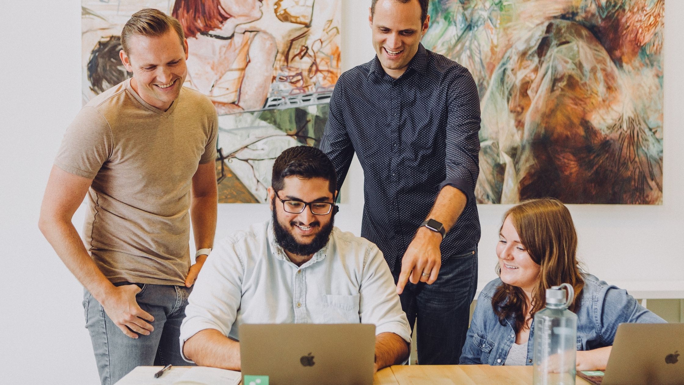 A group of colleagues huddled around a computer
