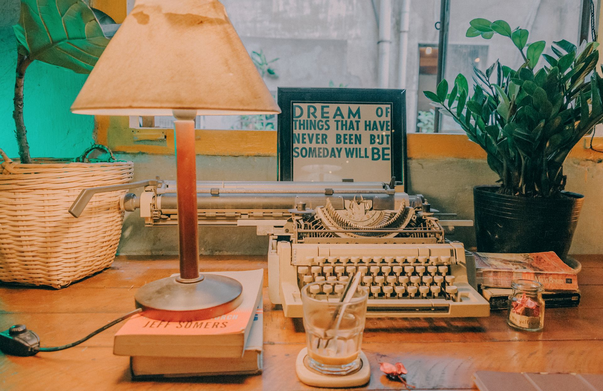 A desk in a serene environment with a typewriter and a quote clock displaying a daily author's quote.