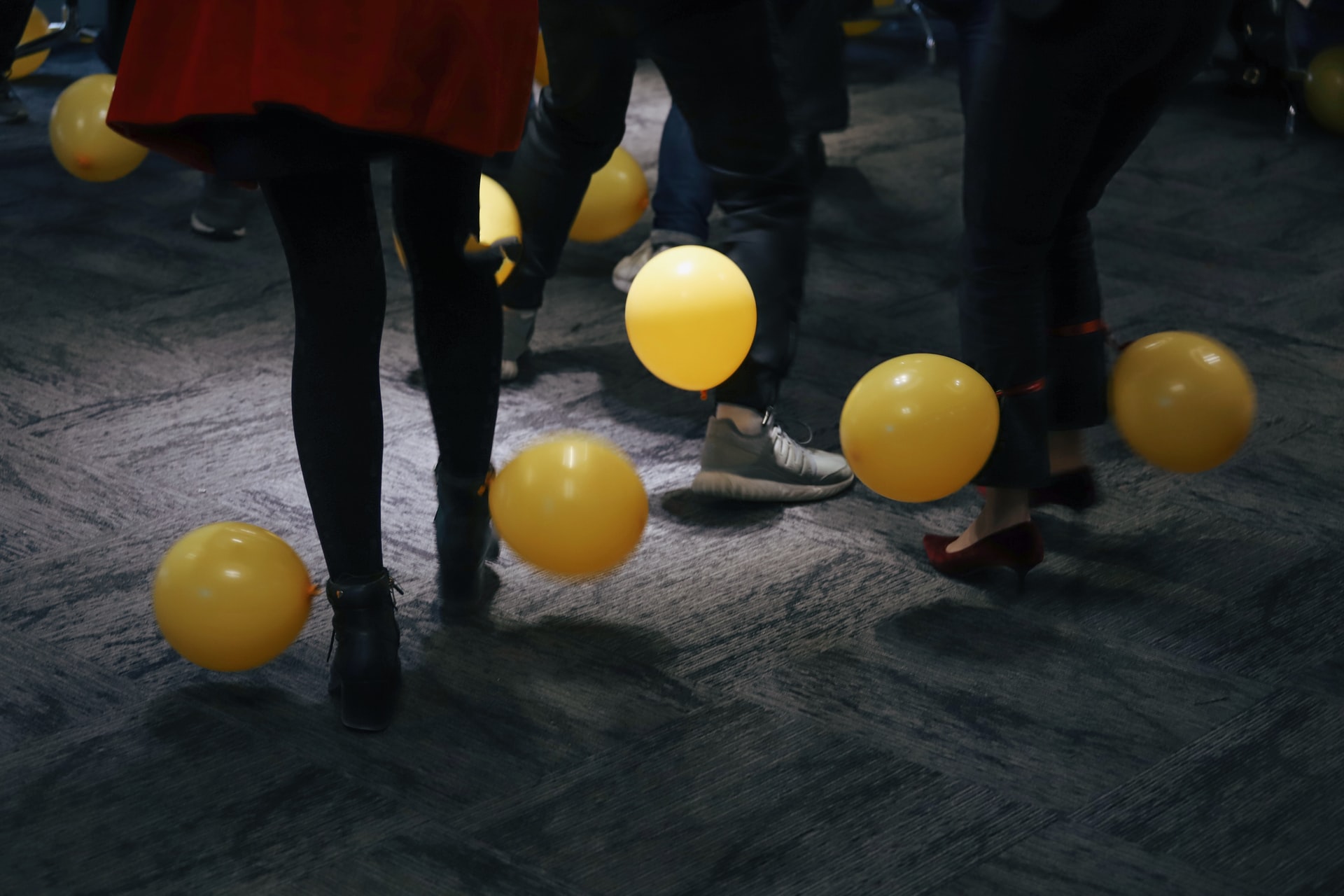 Party Guests kick yellow balloons about  
