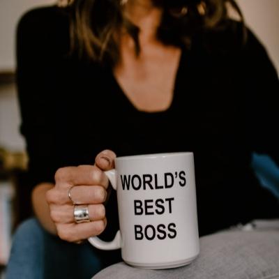 A woman holds a mug that reads "Worlds best boss"