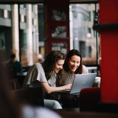 Two women around a laptop laughing