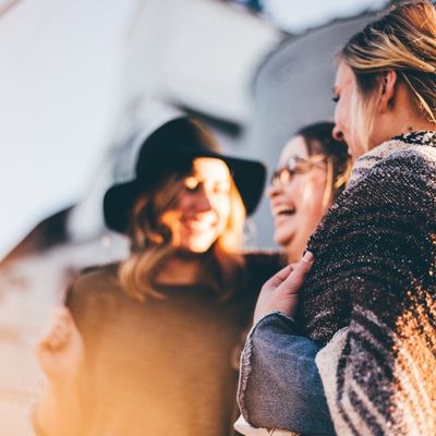 A group of three friends smiling at each other 