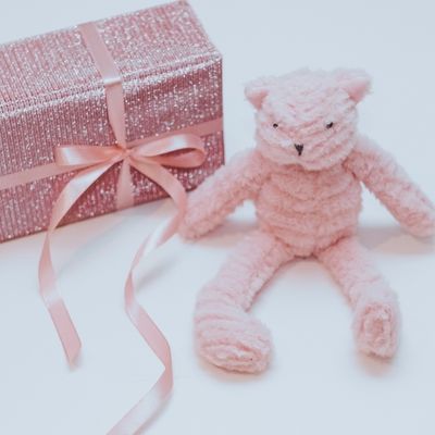 A pink teddy next to a sequin-wrapped gift with a bow