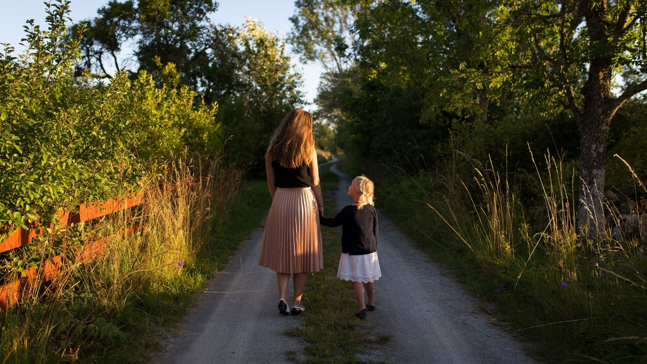 A mother & daughter hold hands. 