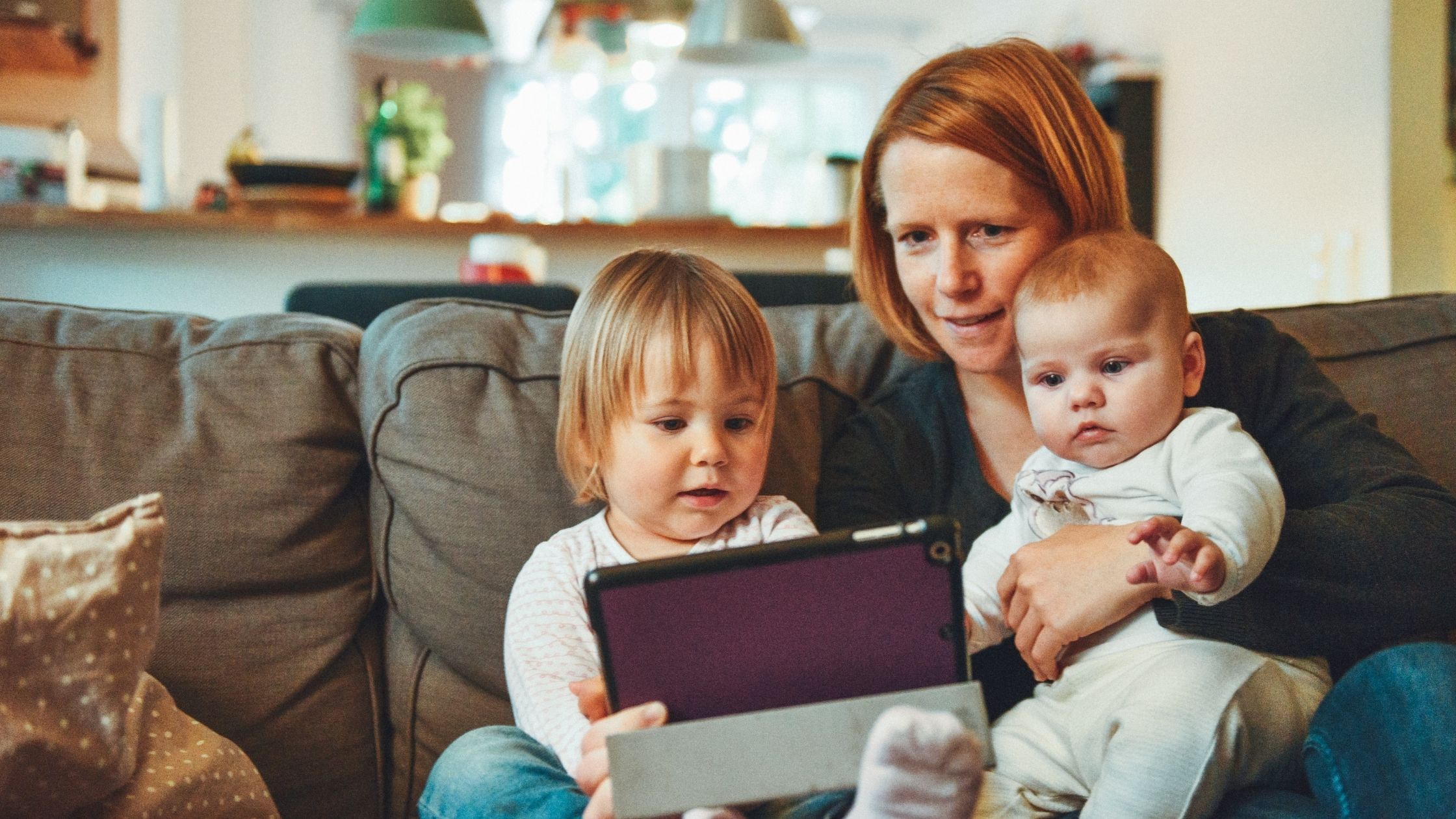 A mother and her children sit on the sofa