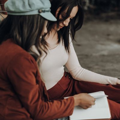 Two people sat on a bench looking at a notebook