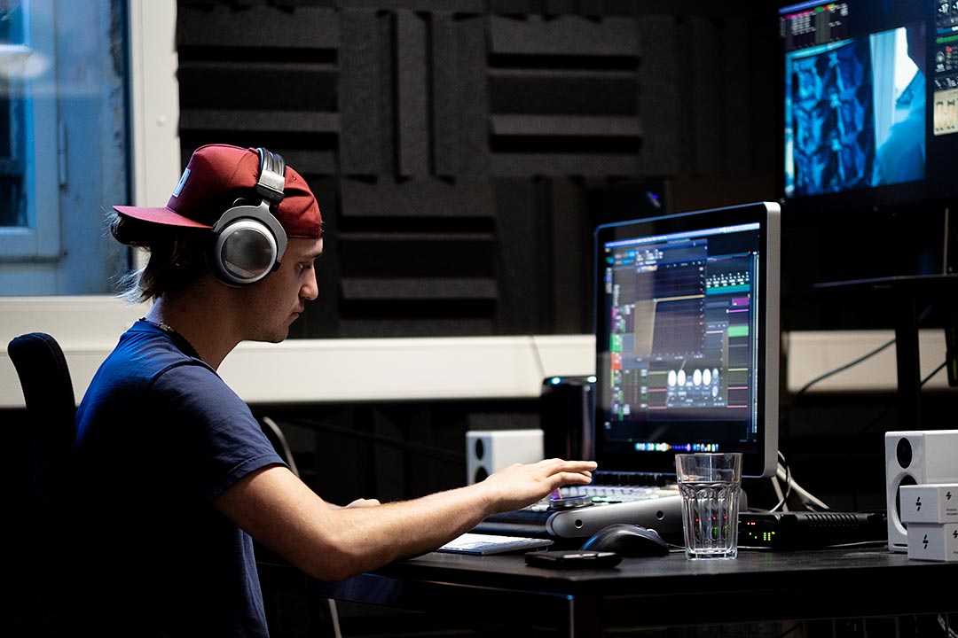 Mann mit Kopfhörer im Tonstudio vor dem Computer