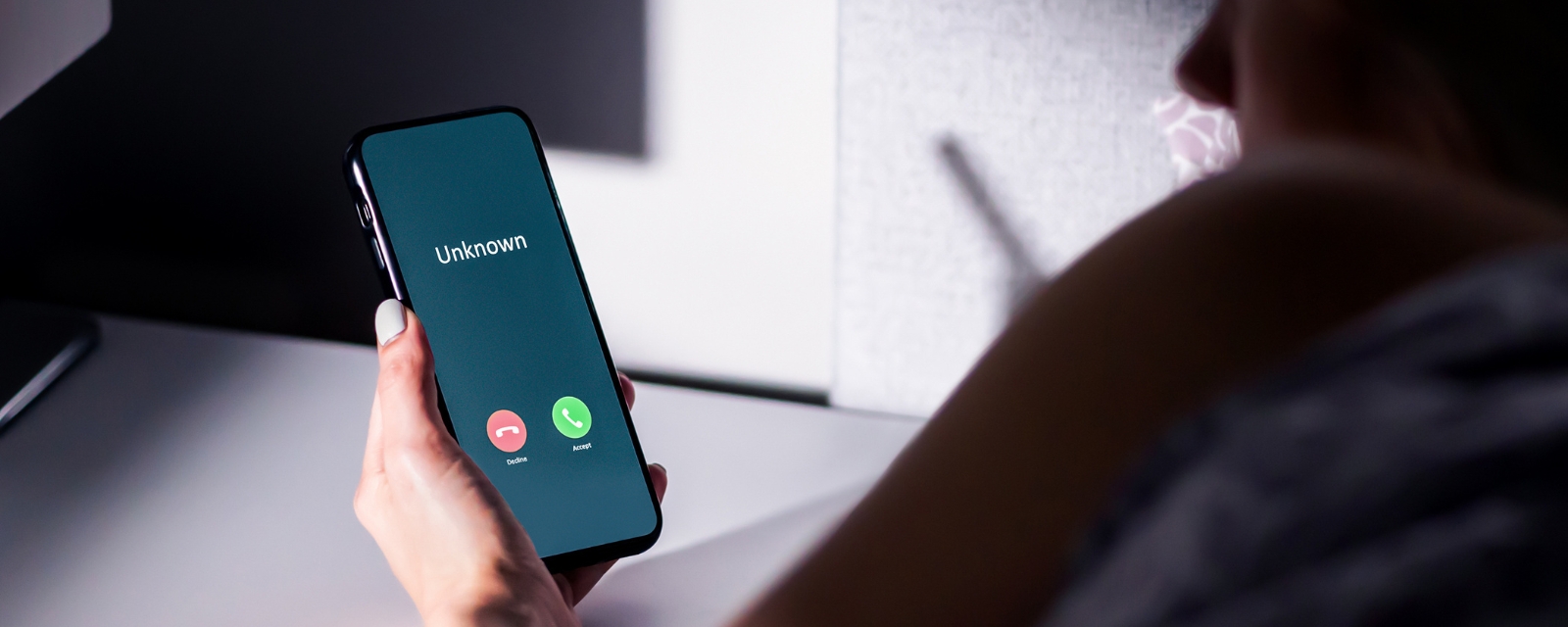 Woman in bed at night getting a phone call from unknown number. 