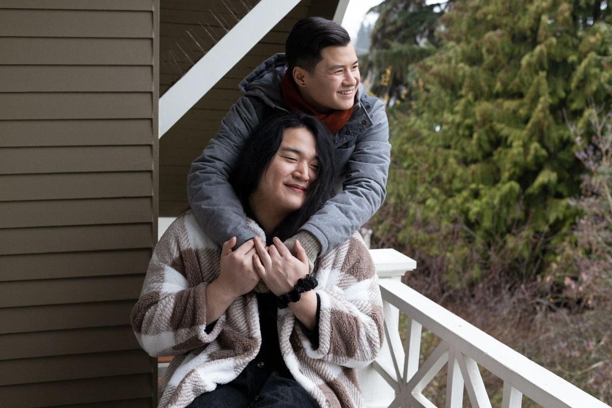 Asian American trans cuddling hugging on a balcony of a lodge.