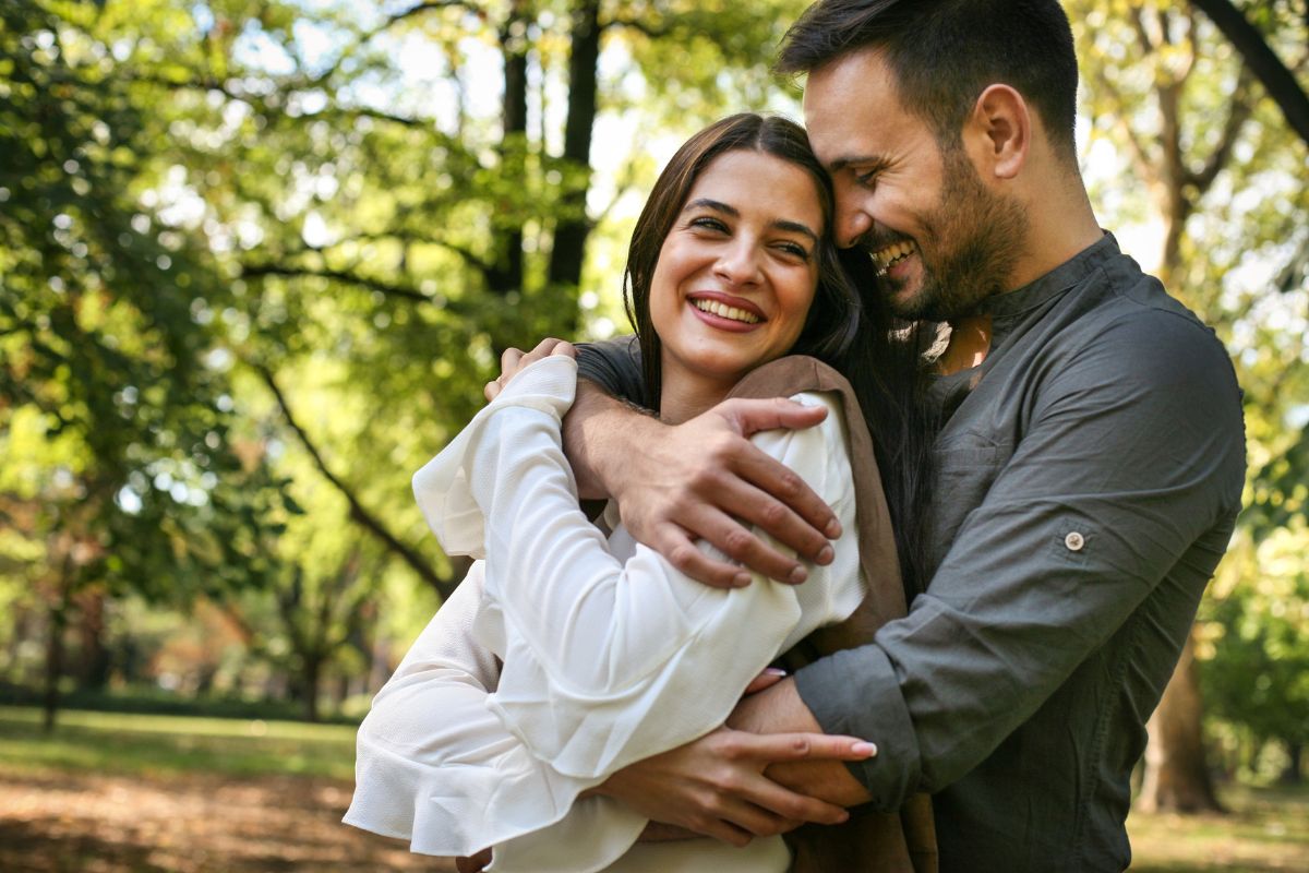 Man embrace woman in a hug from behind both happy and smiling in love.