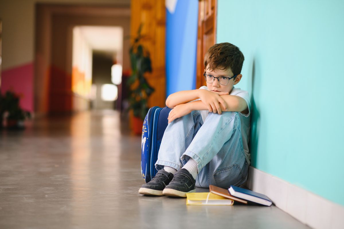 Young boy sitting alone with sad feeling at school.