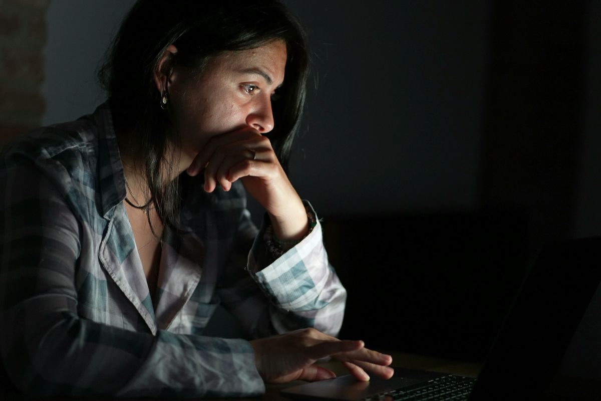 Person reading content online at night in front of laptop screen