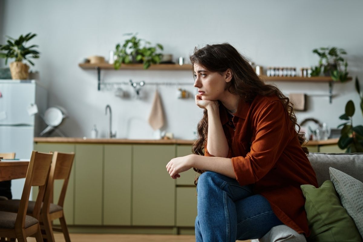 Woman sitting alone in a cozy kitchen reflecting on feelings of sadness and isolation