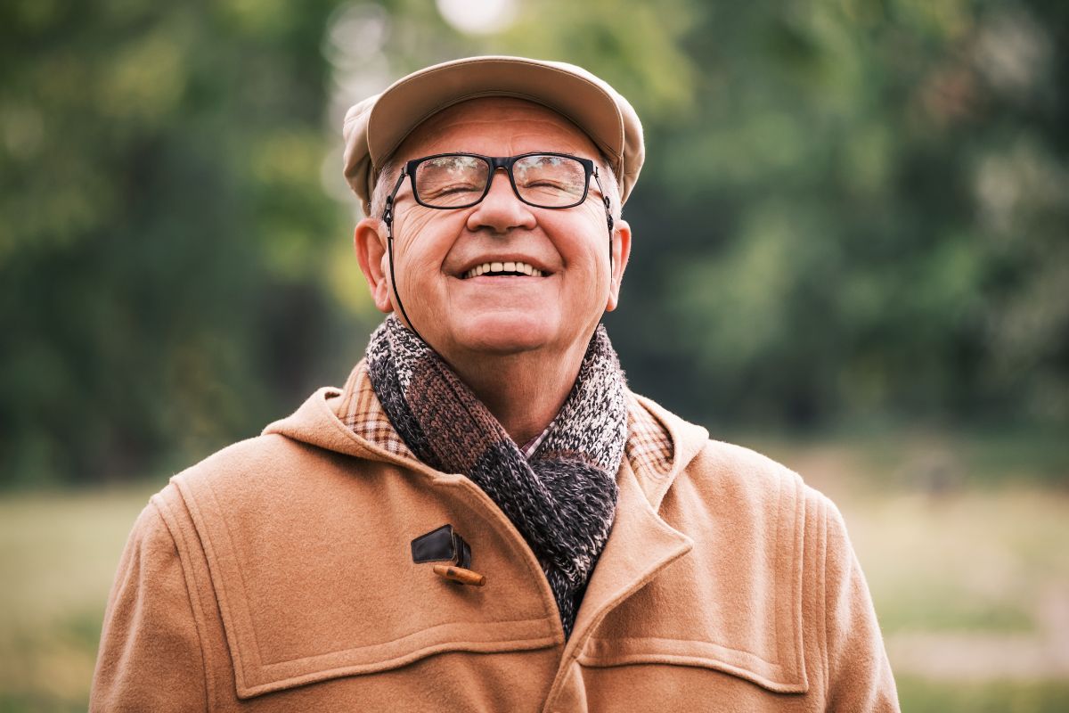 Happy senior man is enjoying fresh air in park.