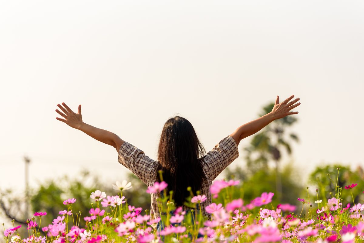 Happy woman raised open arms in flower garden, lifestyle and healthy confidence relax woman concept.