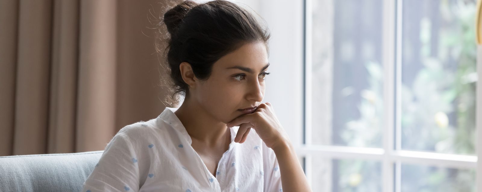 Sad Indian woman sit on armchair looks concerned, feels confused, thinks, search solution in difficult life situation, hesitating seated alone at home.