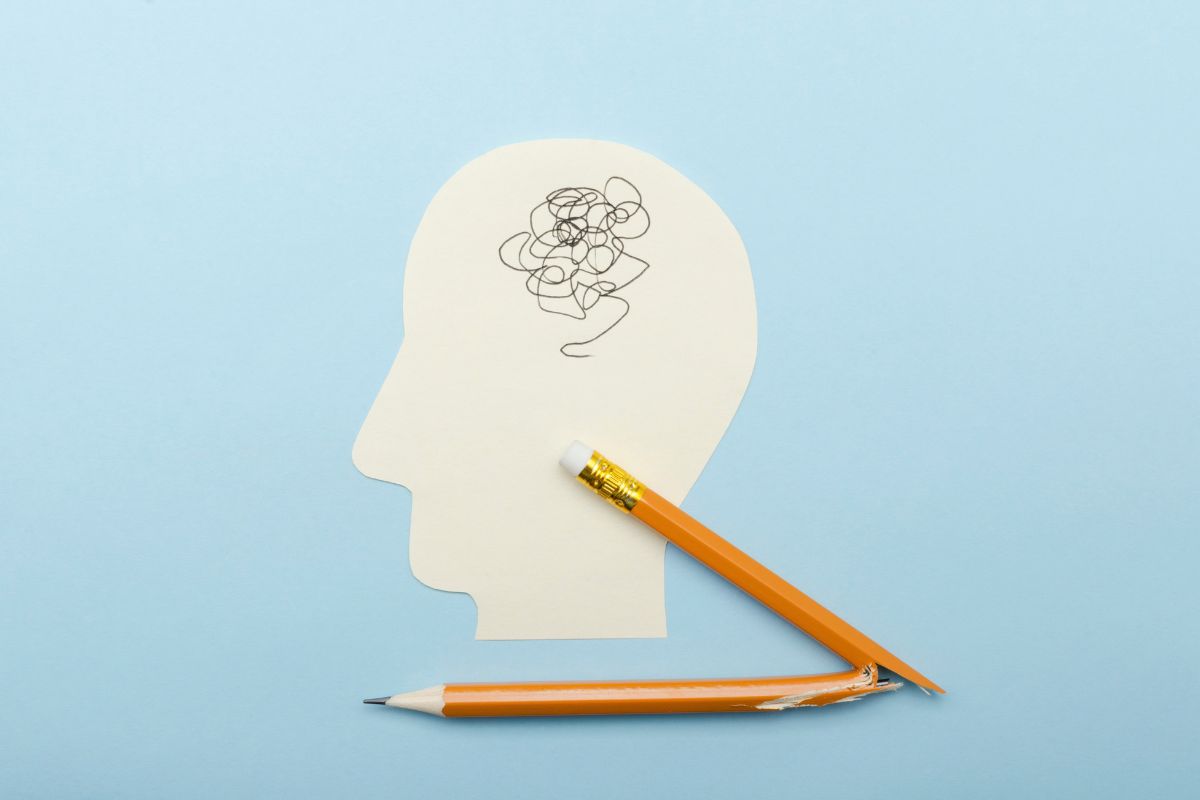 Image of a head with tangled squiggles in mind and a broken yellow pencil laying on the bottom middle of the image