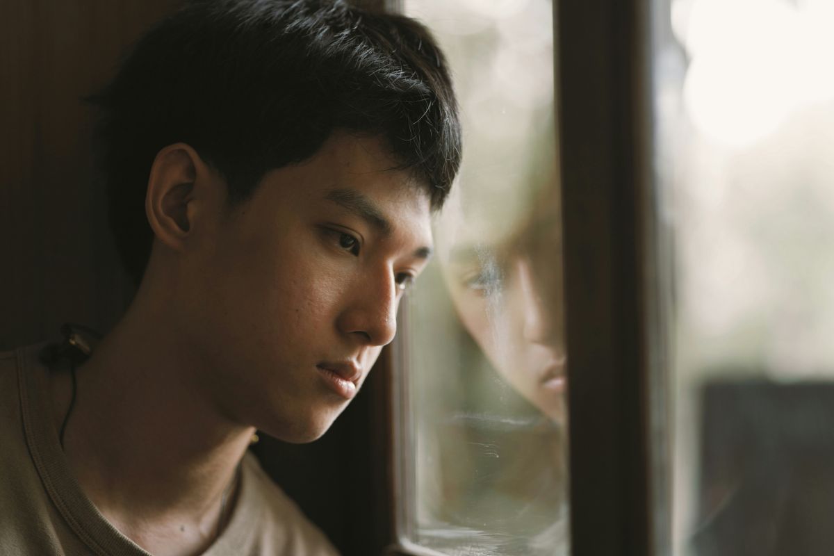 Close up of a sad young Asian man looking out the window