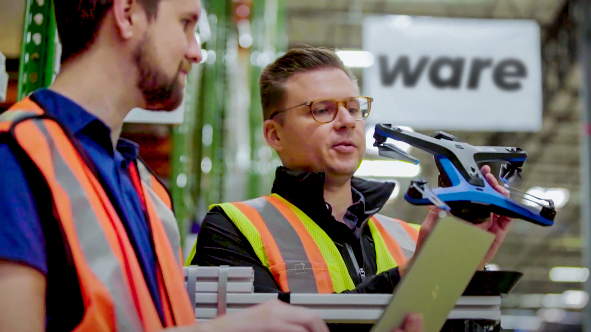 Ware's CEO Ian Smith holding a drone in a warehouse and CTO Joe Moster