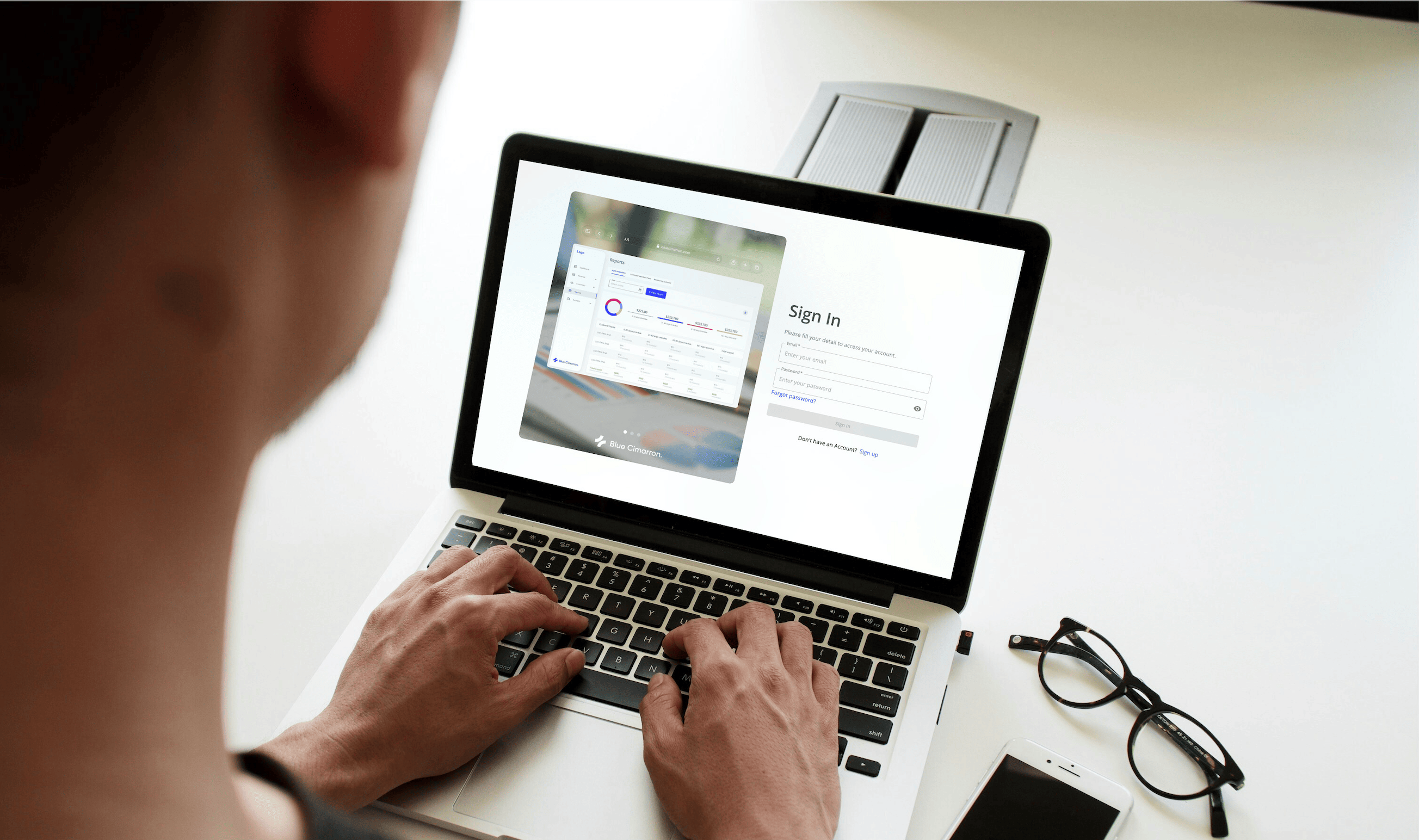 A person signing in to the Blue Cimarron billing platform on a laptop, next to a preview of its reports dashboard.