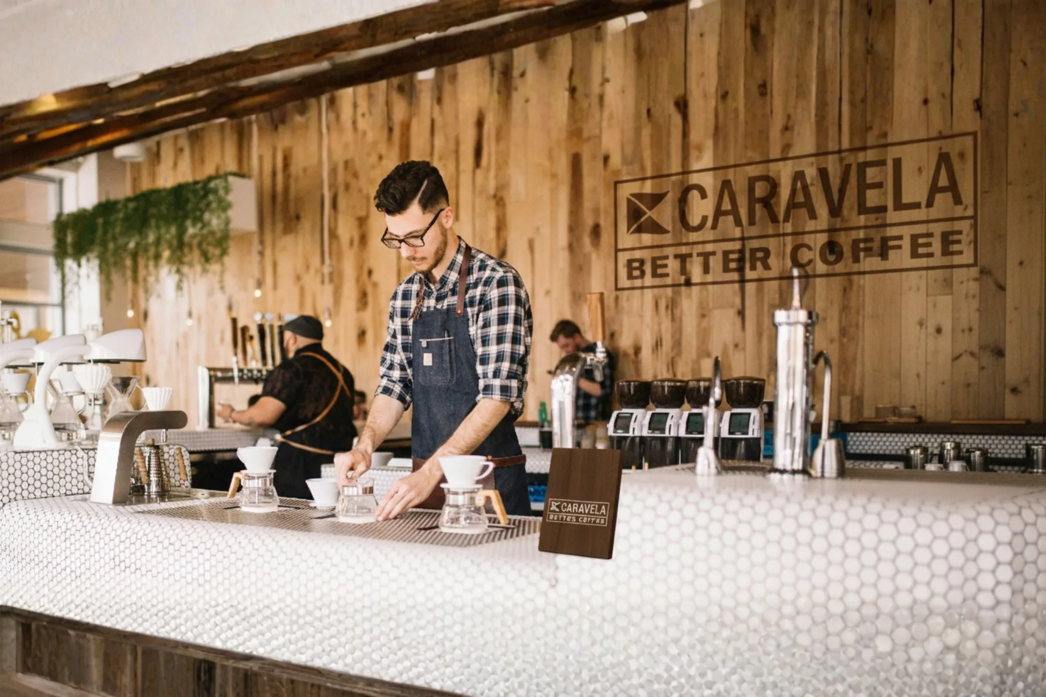A worker in a coffee shop featuring the Caravela logo.